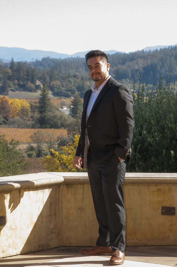 Neil Espinosa, Sonoma County REALTOR, standing outdoors with a wine country vineyard behind him